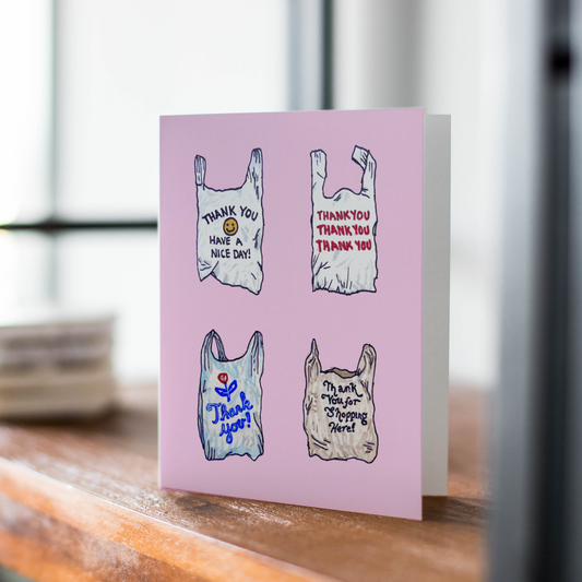 Card with plastic bag illustrations and text on a pink background, placed on a wooden surface.